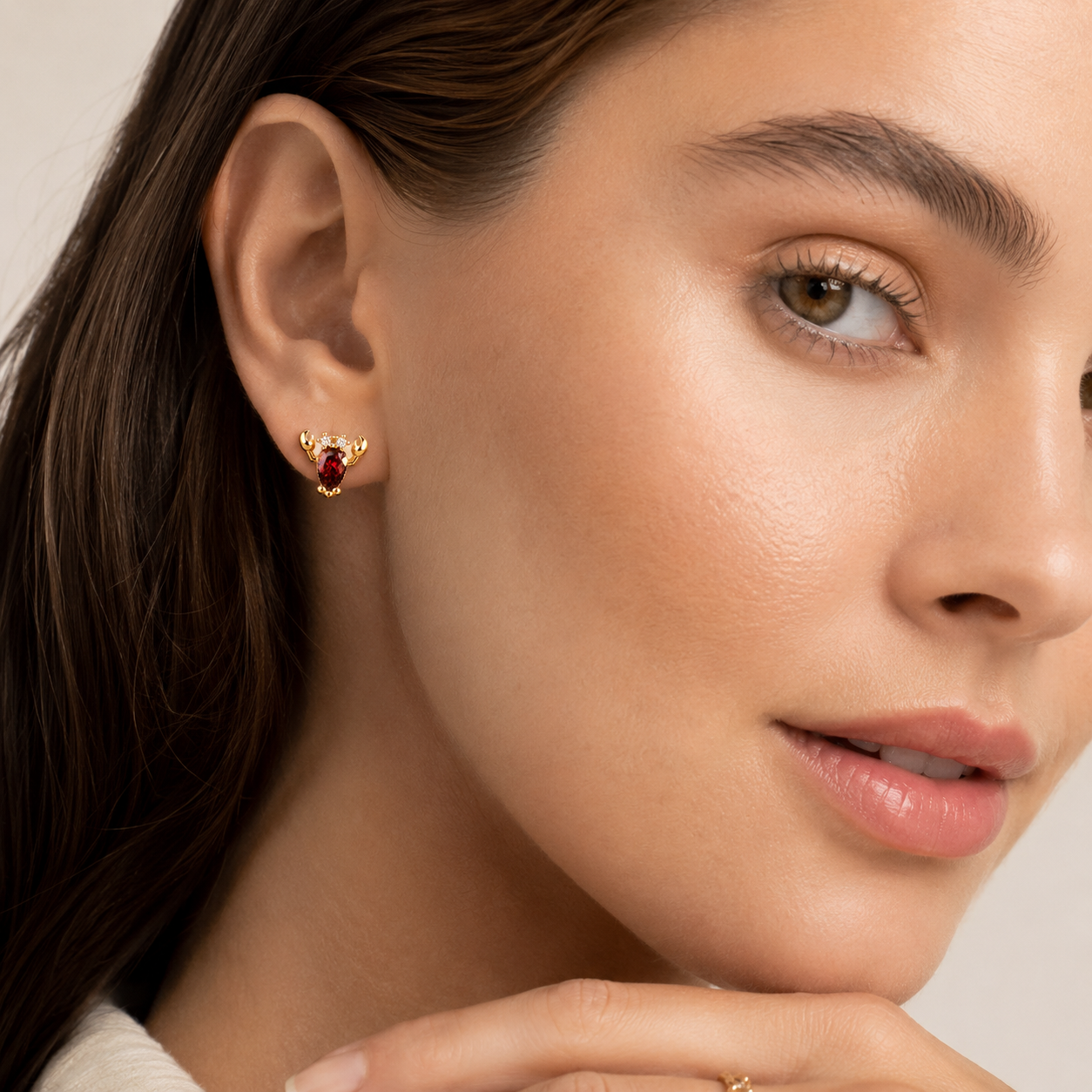 A model wears a gold Little Lobster EARRINGS stud with a red pear-cut cubic zirconia body and gold claw details on her ear.