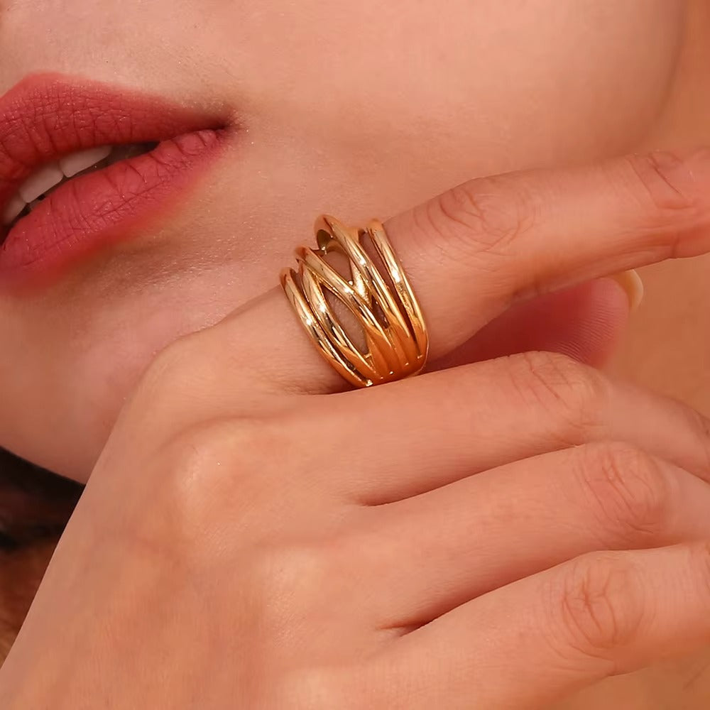 Close-up of a hand near the lips wearing the wide gold wrap-style Lizie RING with its layered wire band design.