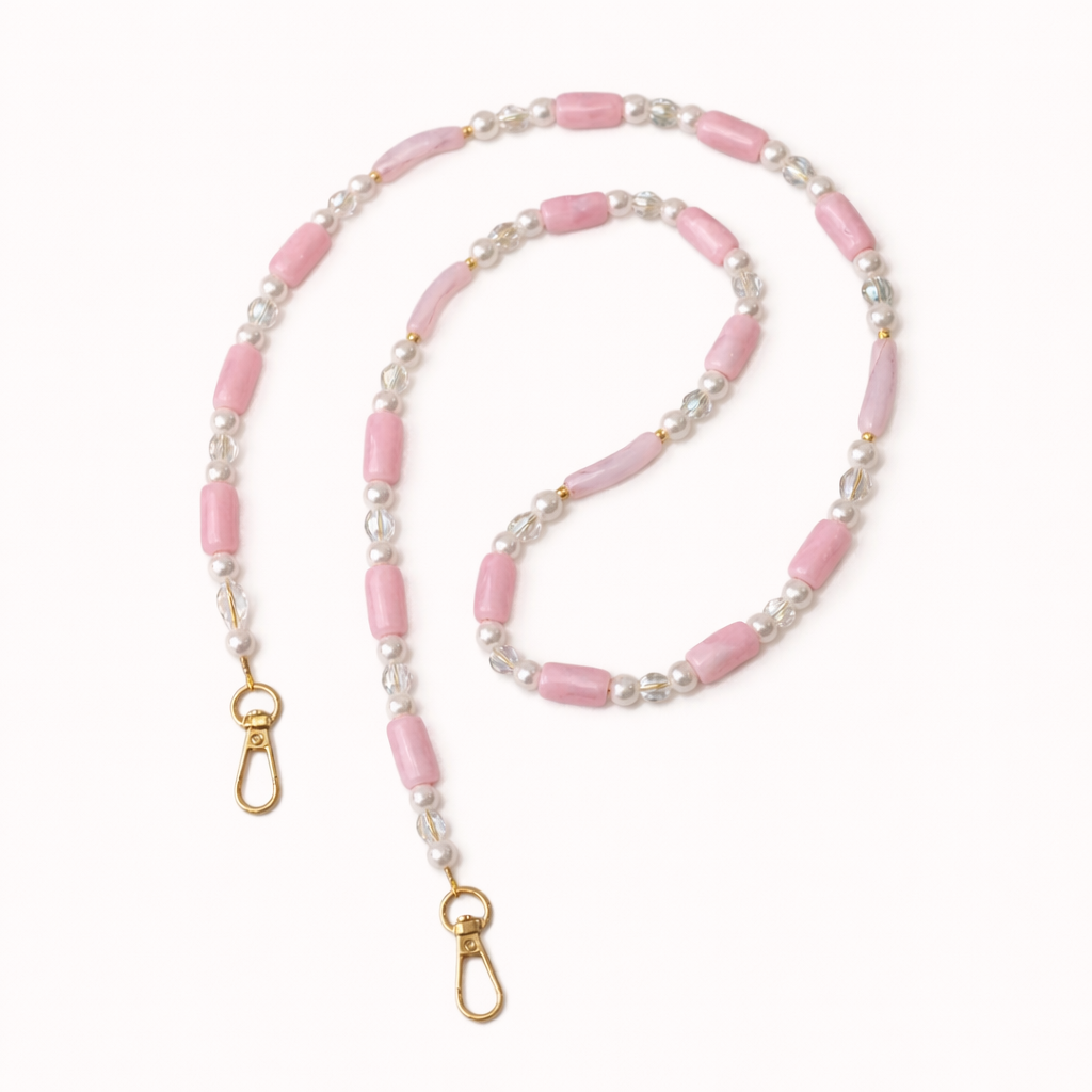 Pink beaded Loreto phone strap coiled flat, accented with pearls, crystals, and gold-tone clasps.