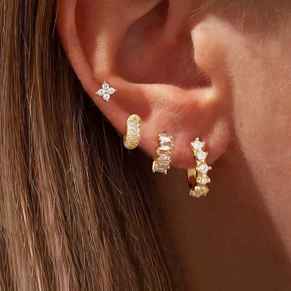 Close-up of a model wearing the four-piece Lou SET gold earrings, including a flower stud, a pave hoop, and two stone hoops.