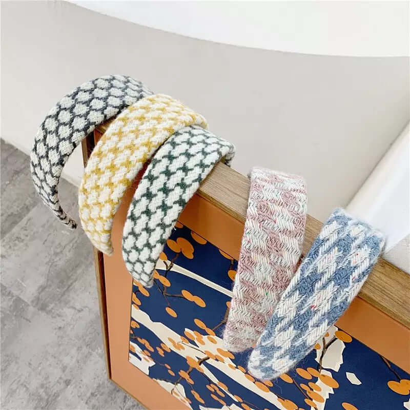 Five padded headbands in grey, mustard and green houndstooth plus dusty pink and blue tweed, draped over furniture.
