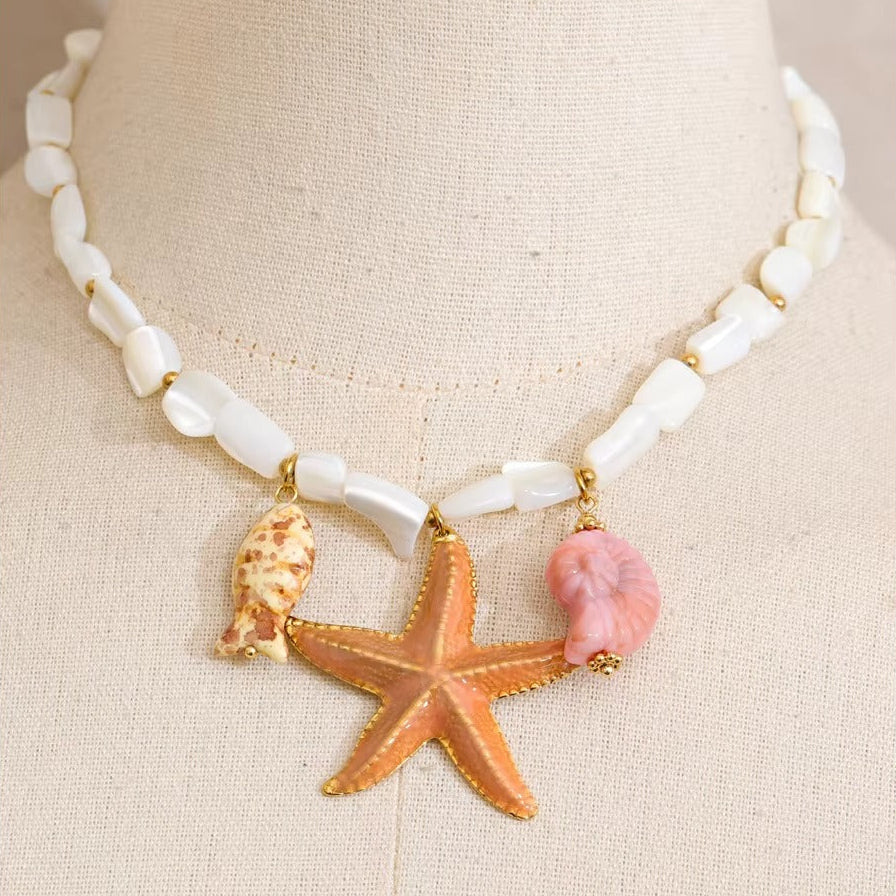The Malibu NECKLACE displayed on a mannequin bust, showing its pearl bead strand and trio of starfish and shell charms up close.