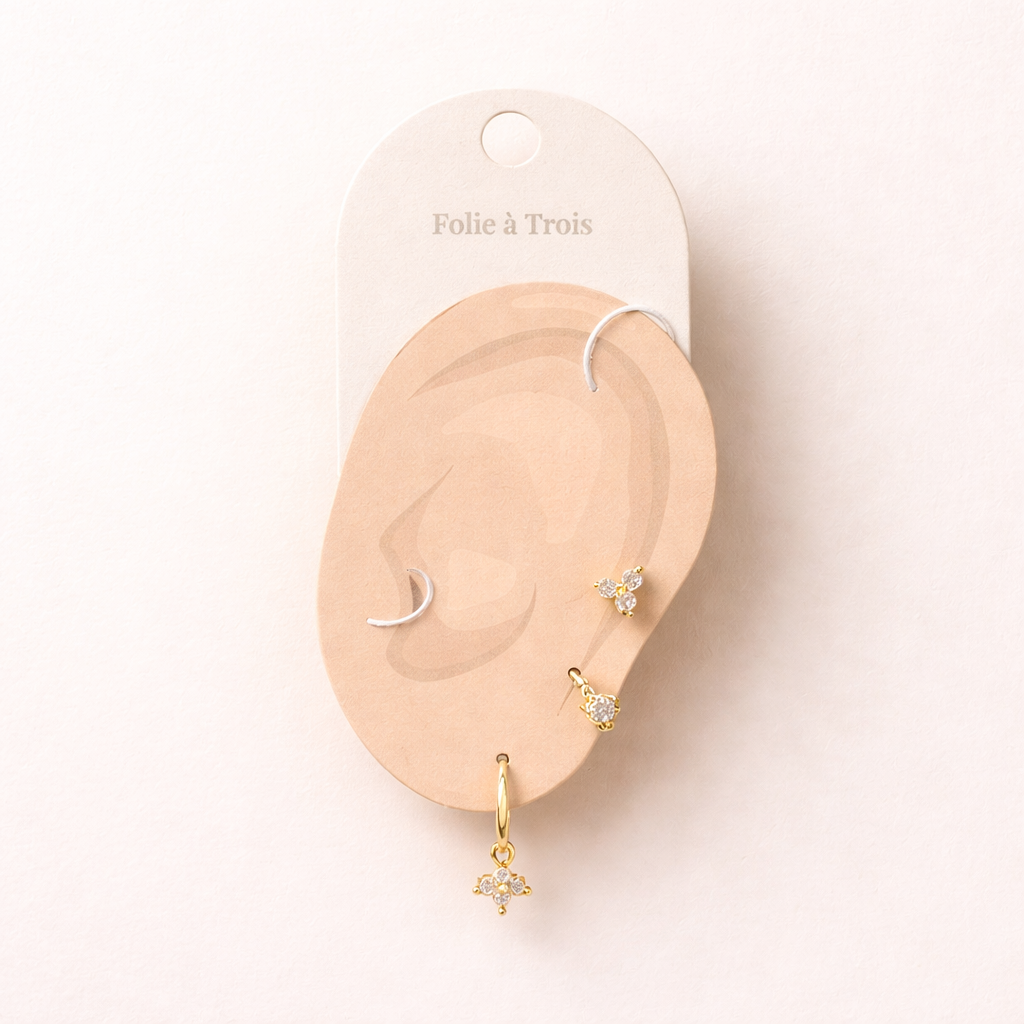 Manon Set displayed on a Folie a Trois ear-shaped card in gold, arranging the stud and crystal-charm hoop for styling.