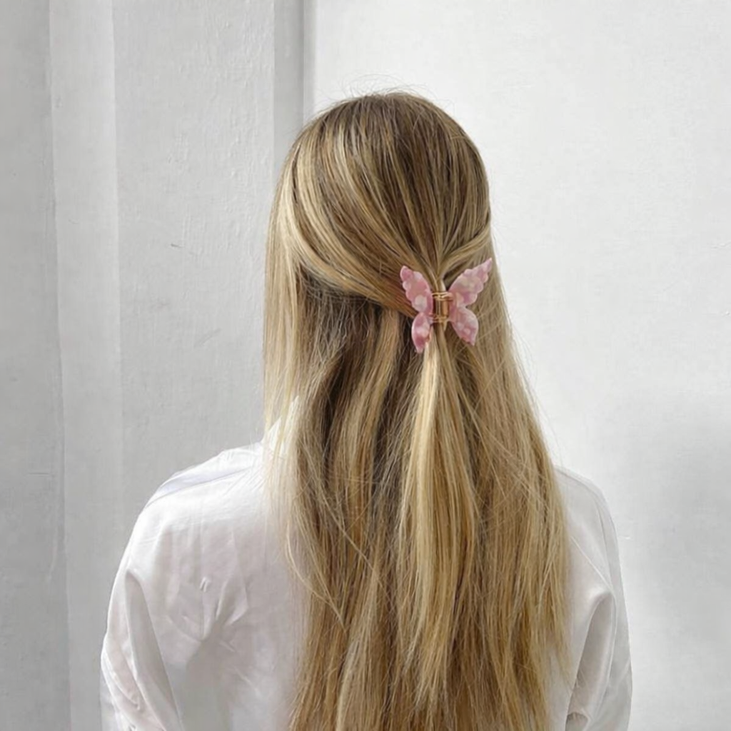 Mariposa HAIR CLIP's pink butterfly clip worn in half-up blonde hair, styled with a white shirt.