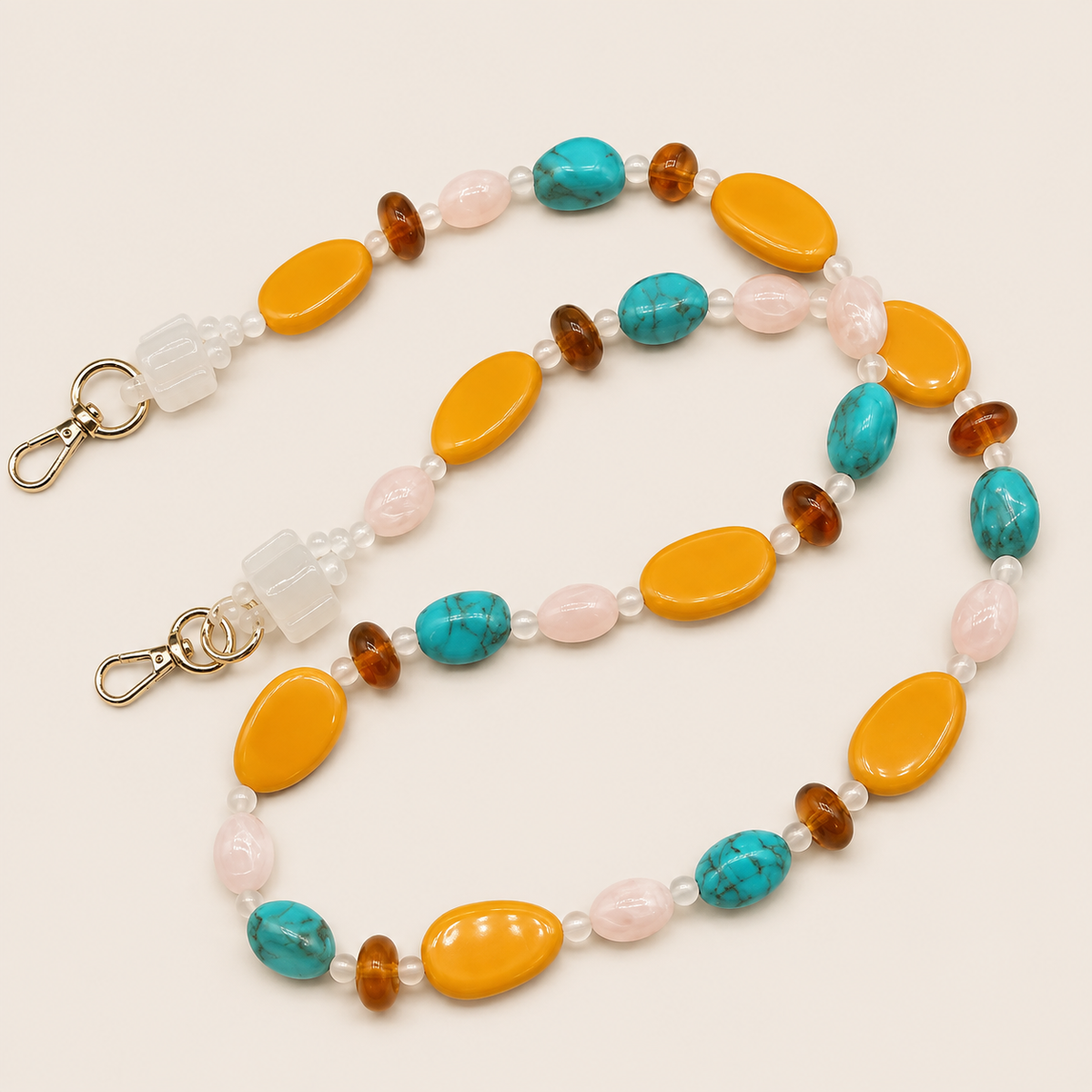 Long beaded phone chain in turquoise, mustard and soft rose tones laid flat on cream — Folie à Trois Marisol long phone chain