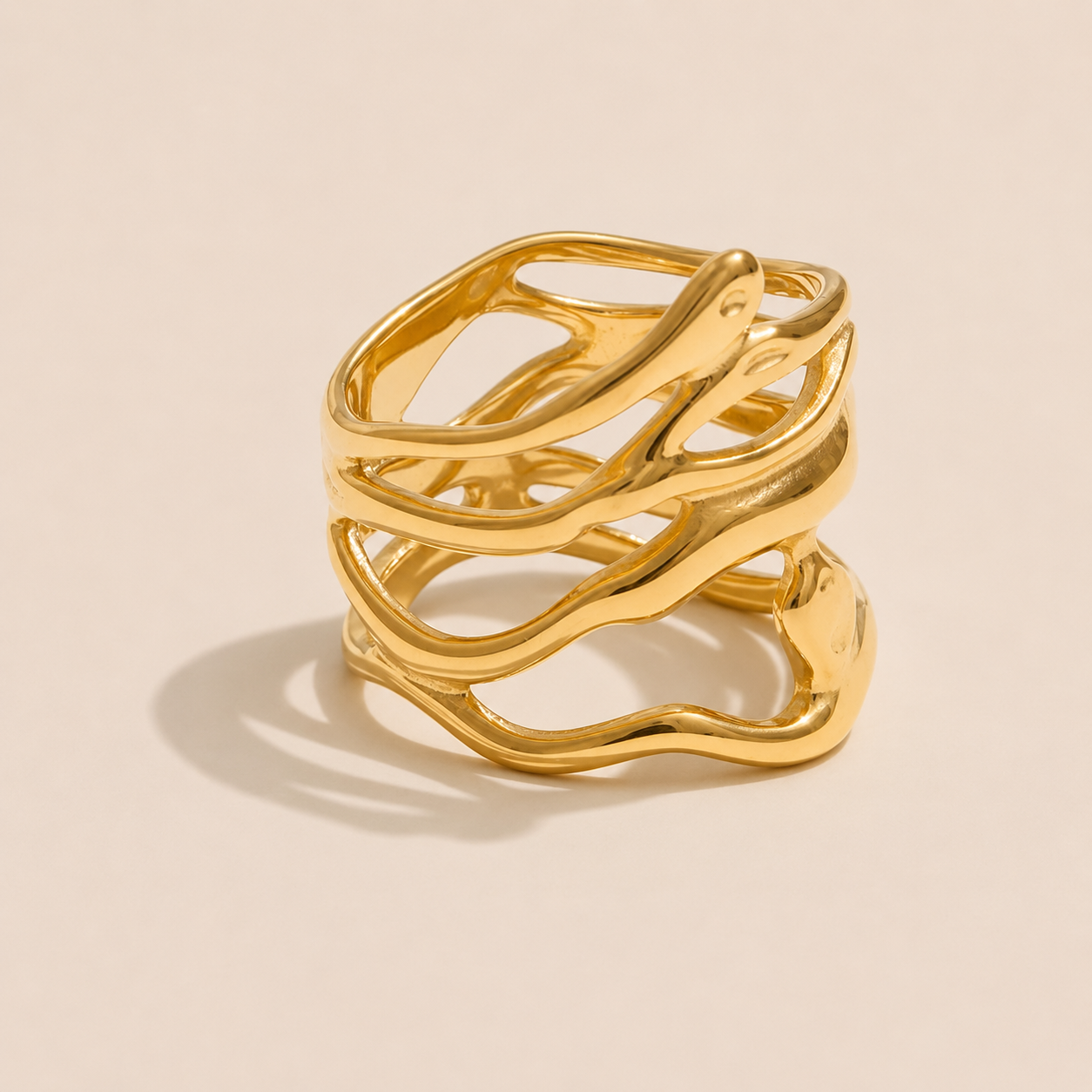 Gold wide cage ring with intertwined organic wave lines forming an open lattice, on a beige backdrop — Folie à Trois Mediterranean Muse RING.