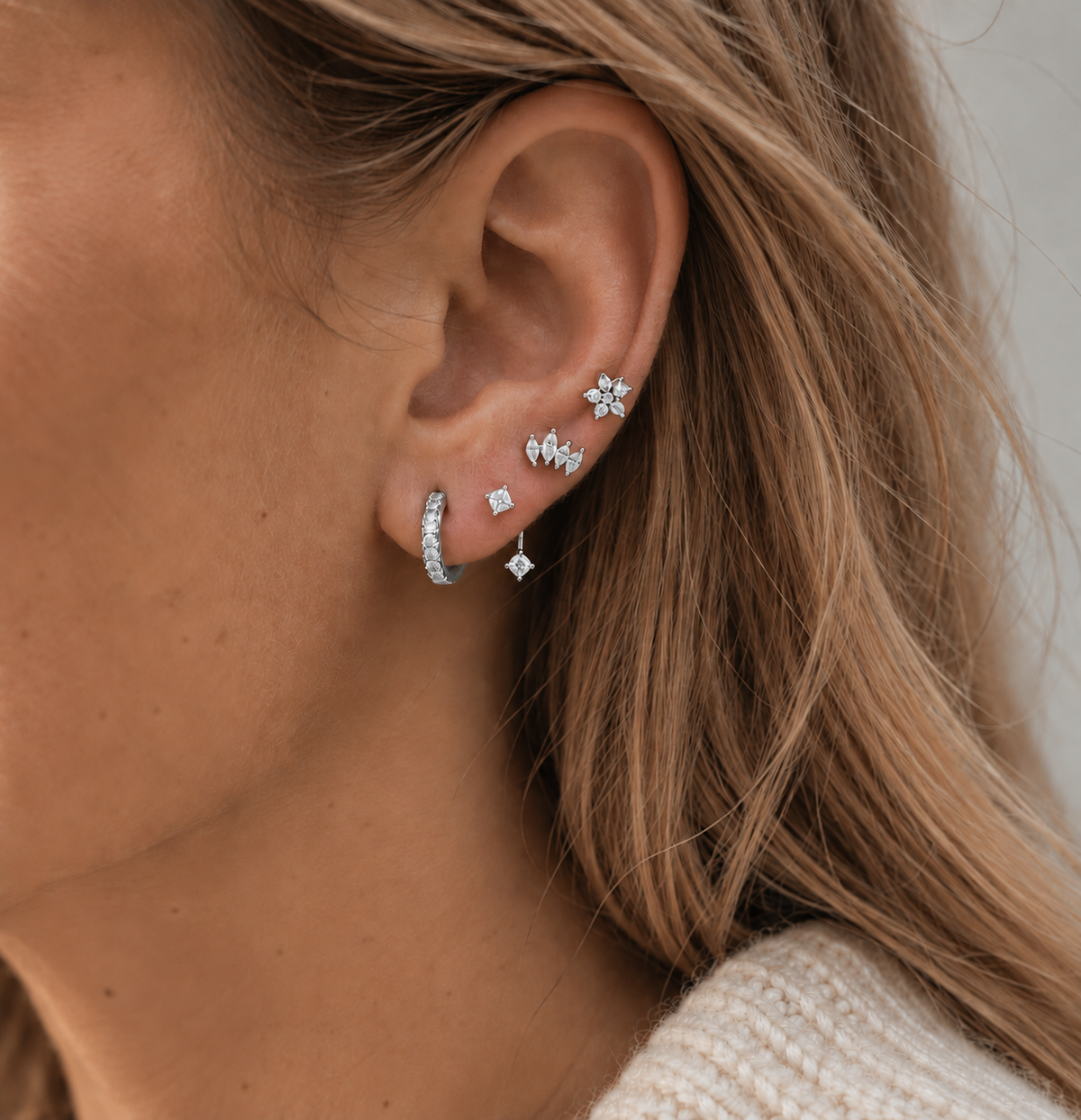 Ear stacked with the silver Melanie SET: a flower stud, a marquise cluster stud, a square chain-drop stud and a pavé huggie hoop.