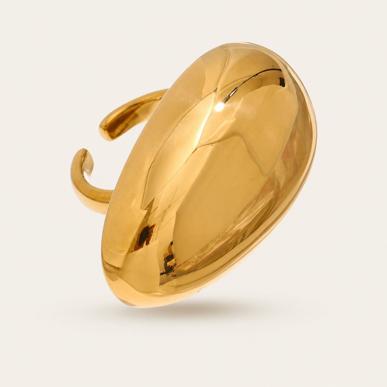 Gold dome ring with a smooth, oversized oval face on a thin open band, shown in close-up on a cream backdrop — Folie à Trois Mirage RING.