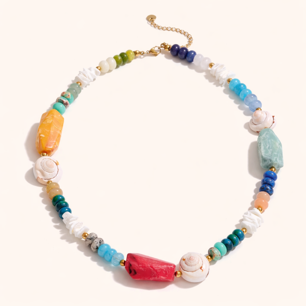 The Mykonos NECKLACE laid flat, its mix of amazonite, coral, lapis, and carved shell beads strung with a gold chain extender.