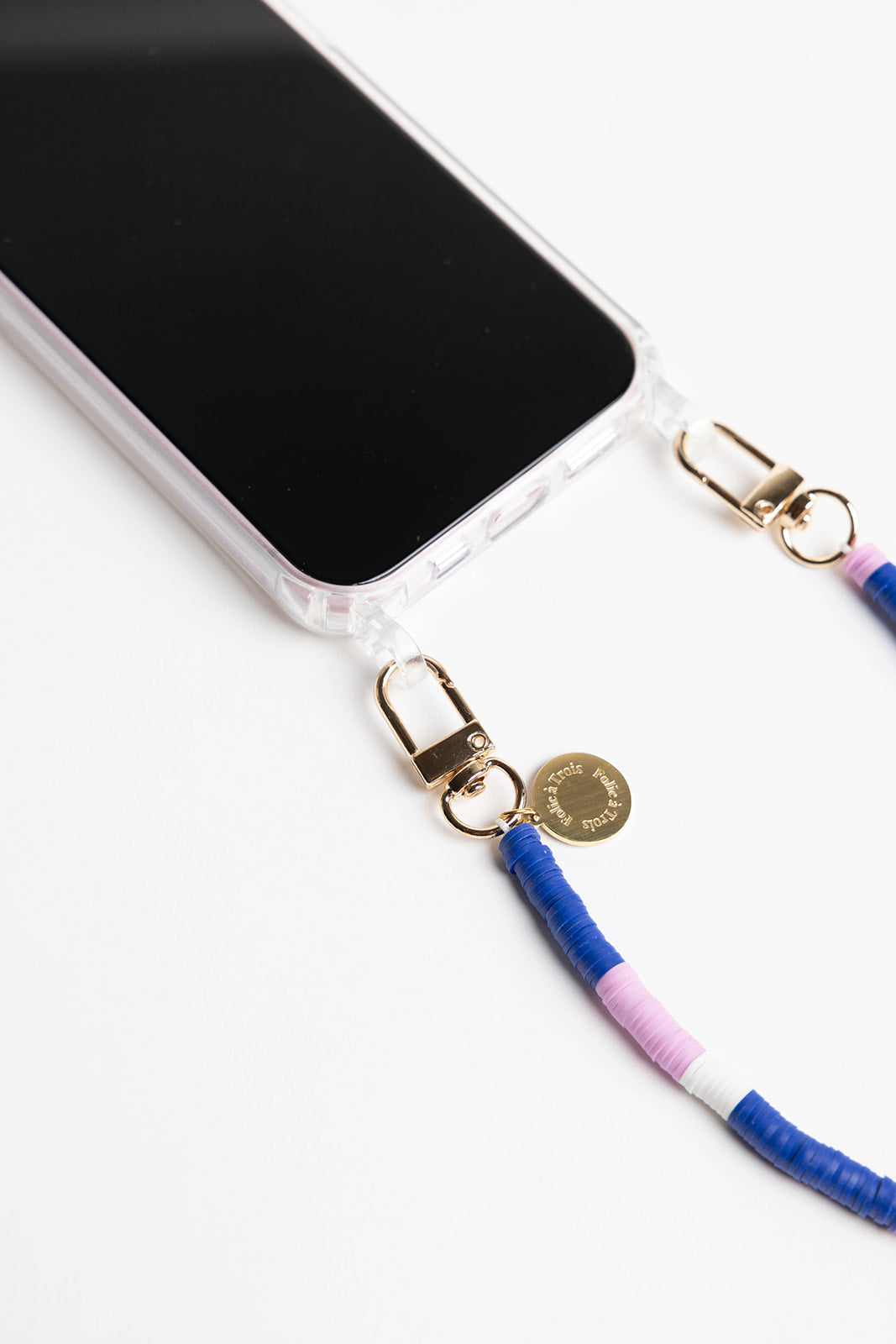 Close-up of the gold clasp and engraved charm on the Popstar SHORT PHONE CORD, with blue, pink, and white heishi beads.