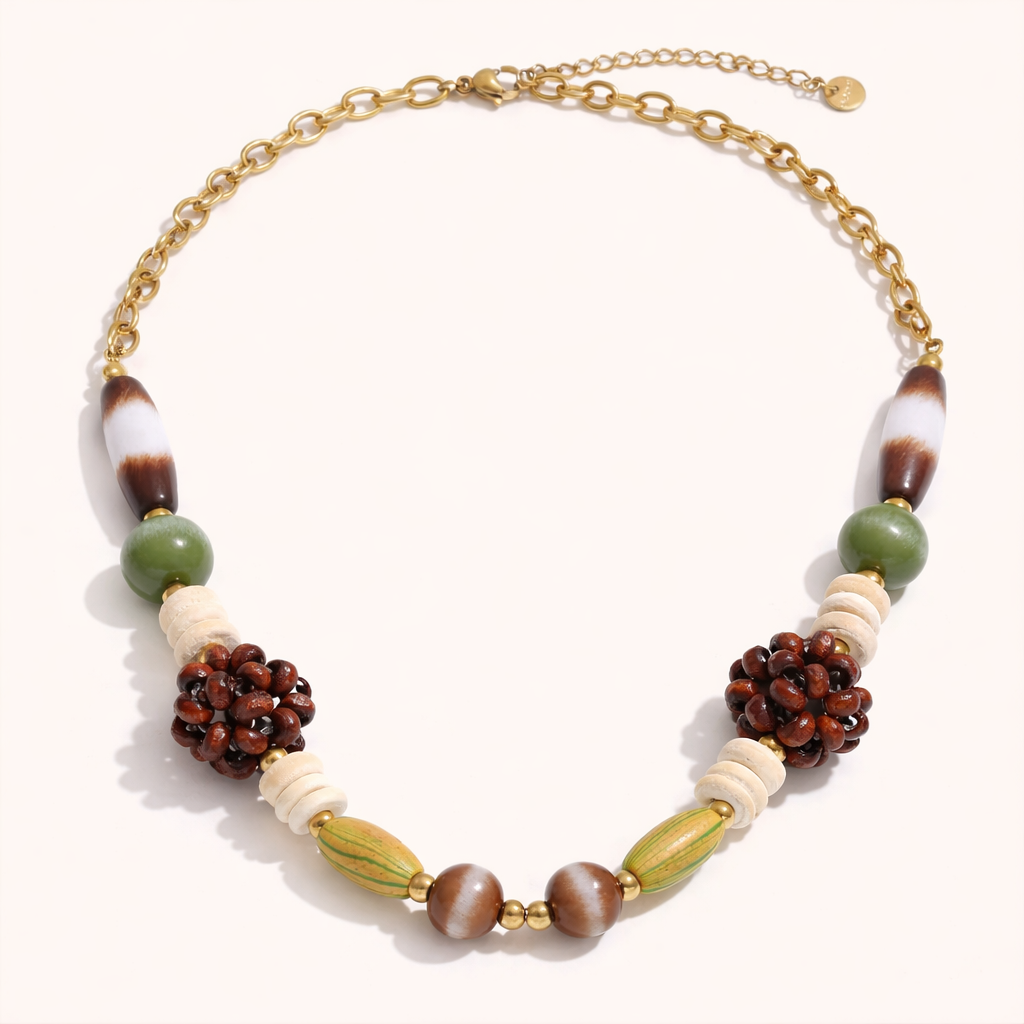 The Rio NECKLACE laid flat, showing striped agate, jade, wood cluster, and tiger's eye beads strung on a gold chain extender.