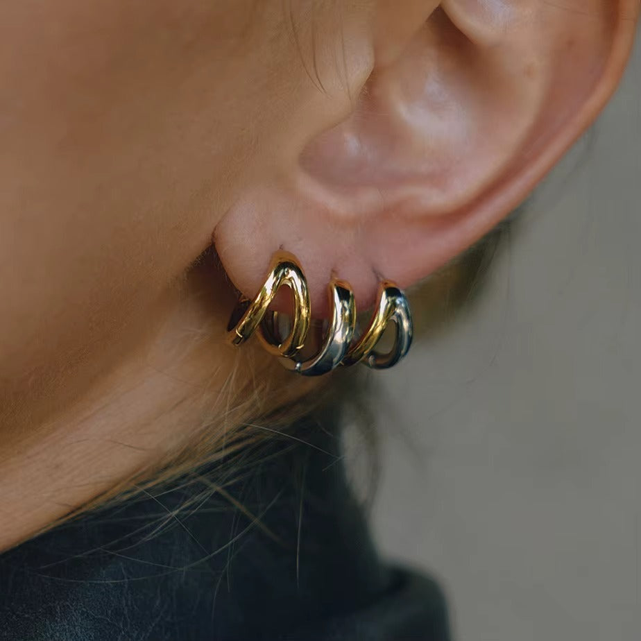 Roadtrip Earrings worn as a stack on the ear, mixing gold and silver chunky double-band hoops close together.
