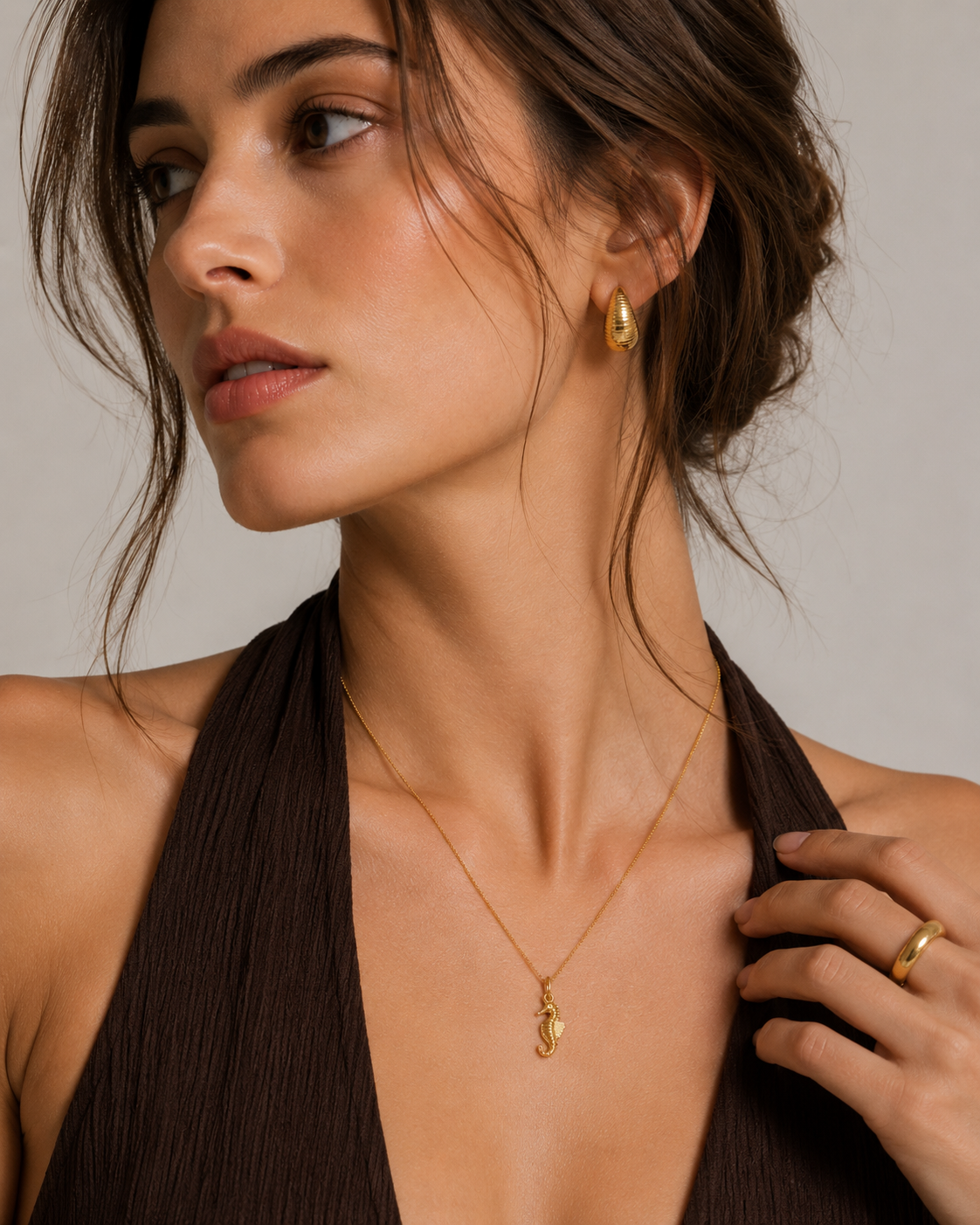 The Seahorse CHARM worn as a pendant on a fine gold chain necklace, paired with matching teardrop stud earrings.