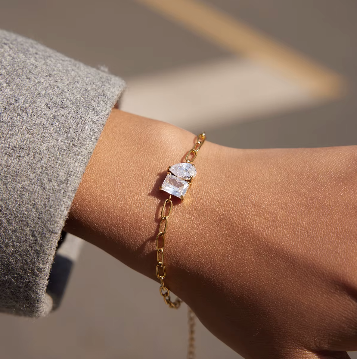 Sharp Halo BRACELET close-up on the wrist with grey sweater sleeve pushed back, outdoor pavement with a yellow parking line.