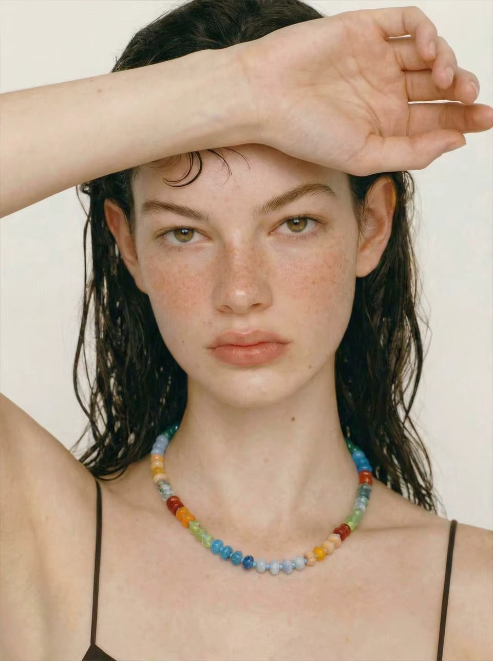 The Sicily NECKLACE worn at the neckline, the model shielding her eyes with wet hair falling loosely around her shoulders.