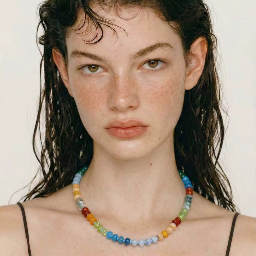 The Sicily NECKLACE worn close-up in a straight-on portrait, the model's wet hair framing her face against a plain backdrop.