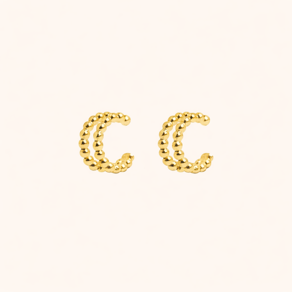 The Solara EAR CUFF in gold, a pair of double-band beaded cuffs shown side by side on a cream background.