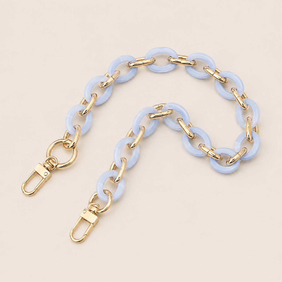 Folie à Trois Sorrel wholesale phone chain in light blue acetate rings with gold links and gold clasps, laid flat on a cream background.