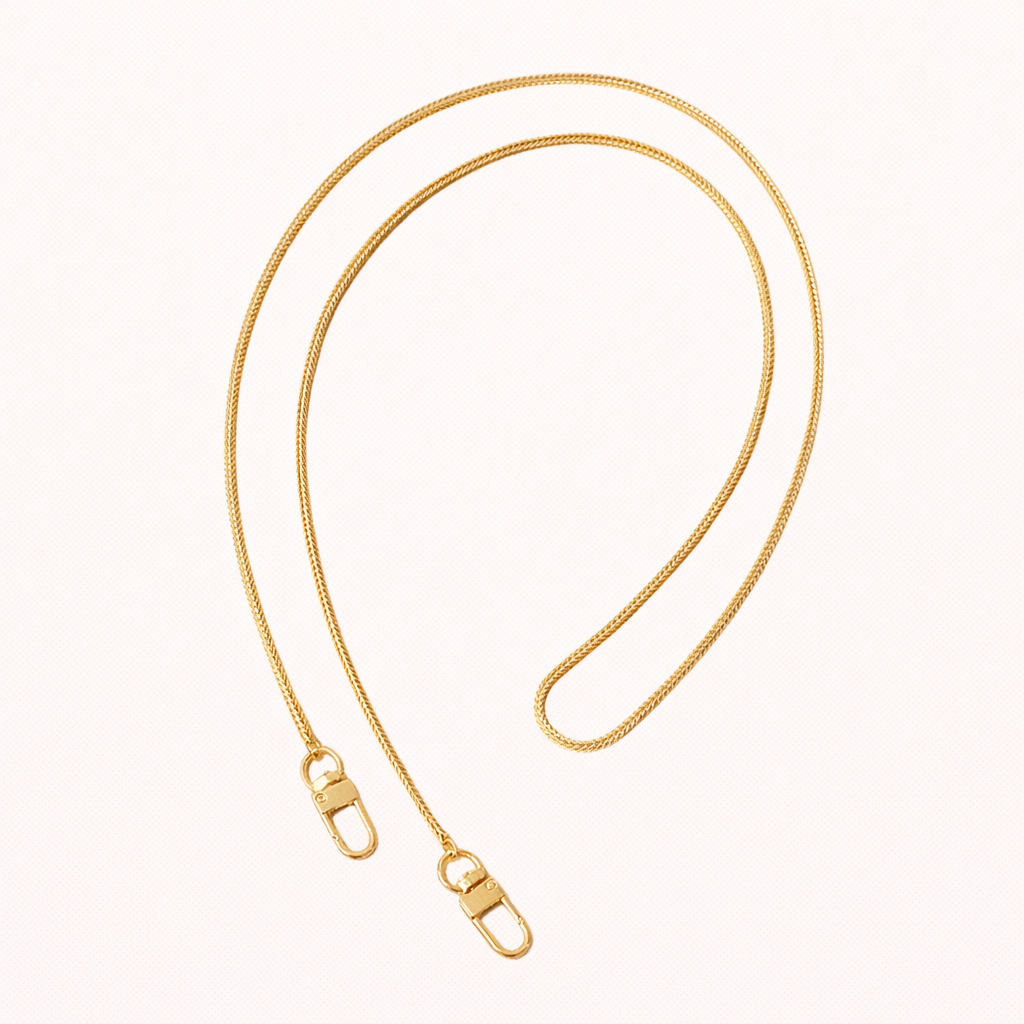 Delicate gold snake-chain phone strap coiled flat, both ends finished with a small lobster clasp.