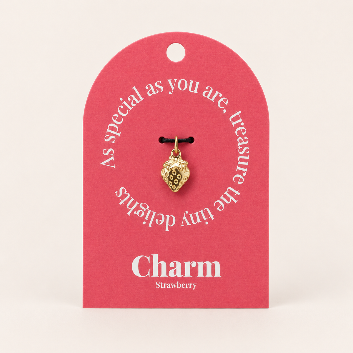 The Strawberry CHARM displayed on a coral pink Charm gift tag, hanging from a black cord against the card's text.