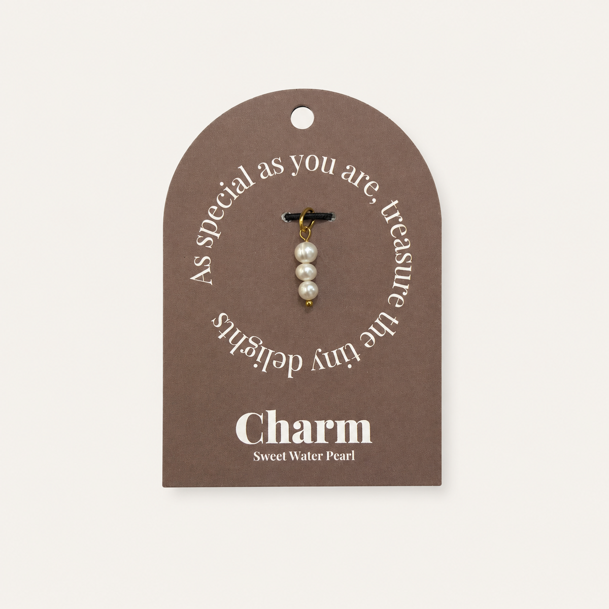 The Sweet Water Pearls CHARM displayed on a brown Charm gift tag, three stacked pearls hanging from a black cord.