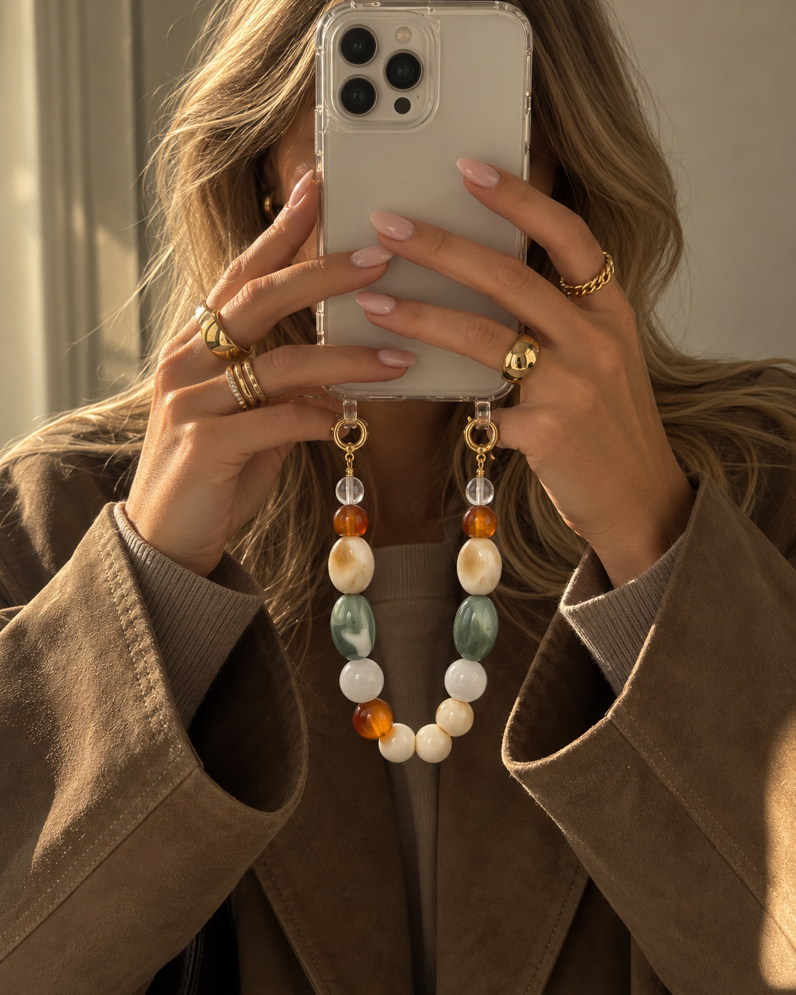 Woman taking a mirror selfie with her phone, the Folie à Trois Talia SHORT PHONE CHAIN's marbled beads dangling from the case.