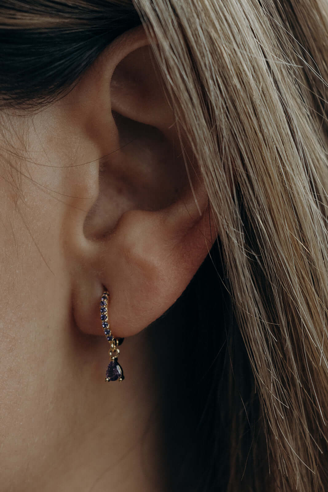 Teardrop Earrings worn on the ear, the pave hoop with sapphire-blue pear crystal drop catching light.