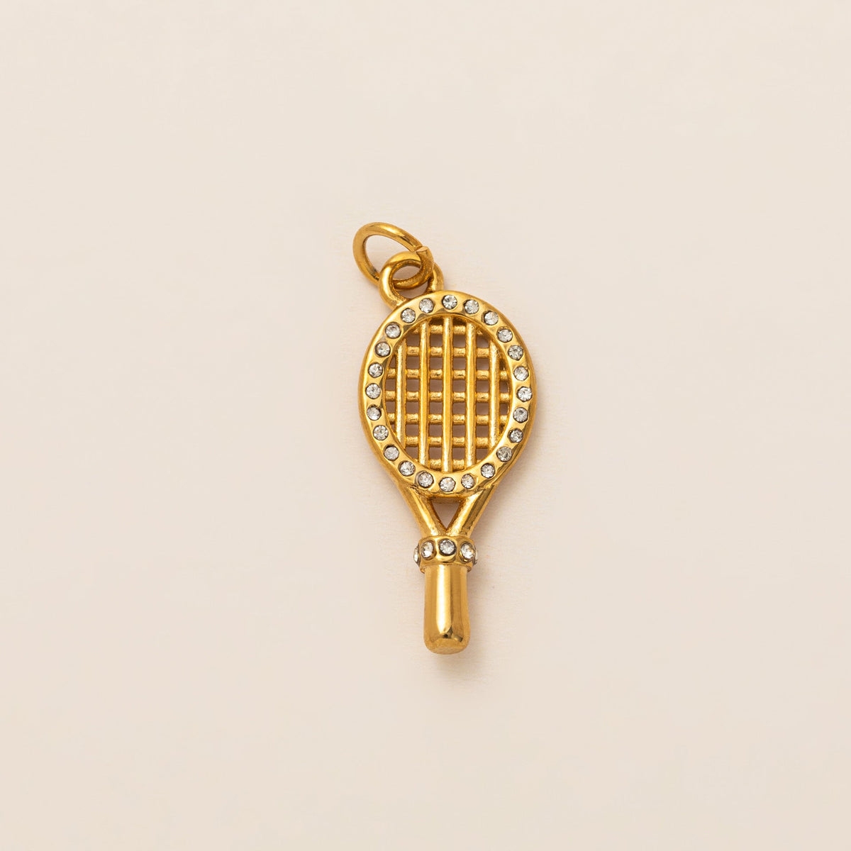 The Tennis Racket CHARM in gold, a racket-shaped pendant with a pave-set frame and grip, shown in close-up studio photography.