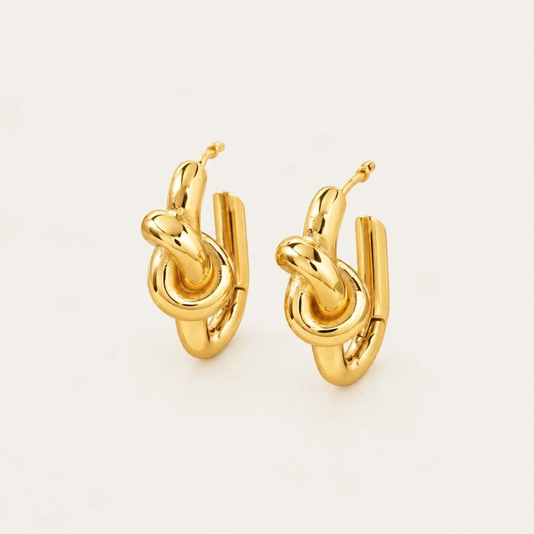 Front view of gold Twine EARRINGS with a polished knotted design on a cream background — Folie à Trois