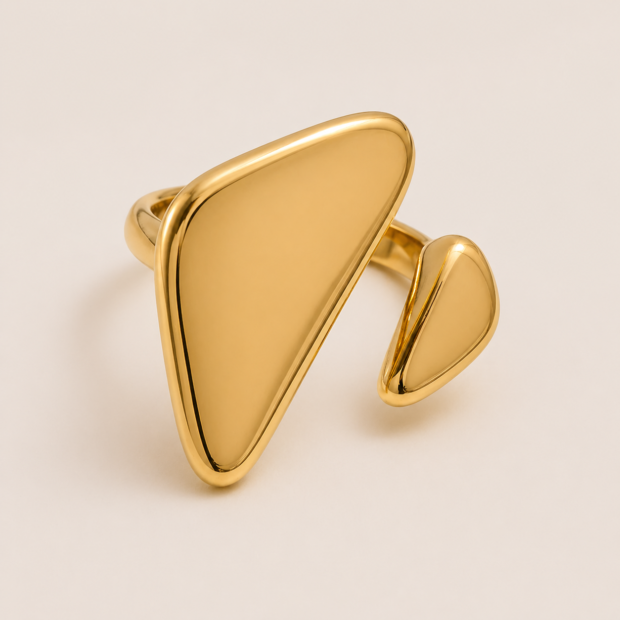 Gold asymmetric ring with a large flat triangular face and a smaller teardrop accent, on a cream backdrop — Folie à Trois Vénus RING.