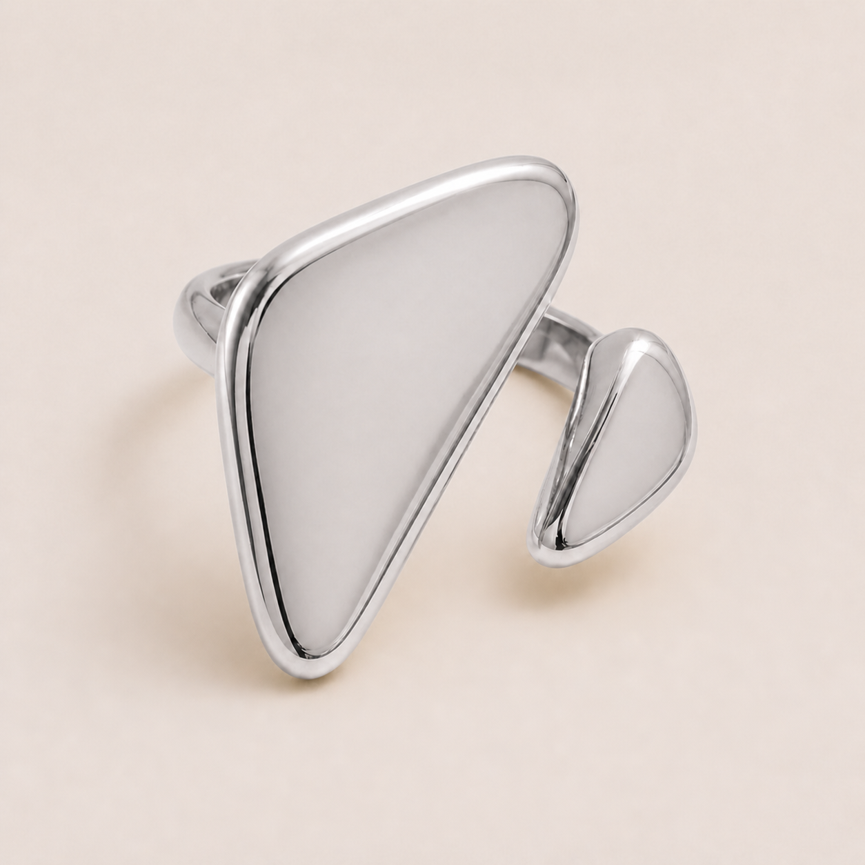 Silver asymmetric ring with a large flat triangular face and a smaller teardrop accent, on a cream backdrop — Folie à Trois Vénus RING.