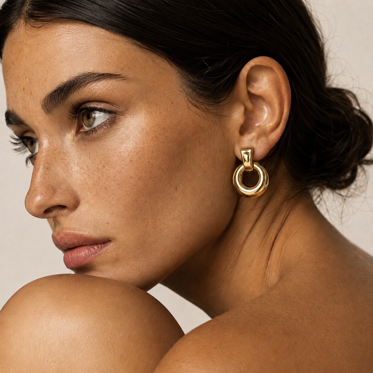 Close-up profile of a model wearing the gold Verve EARRINGS, a chunky doorknocker hoop with a ridged top bar.