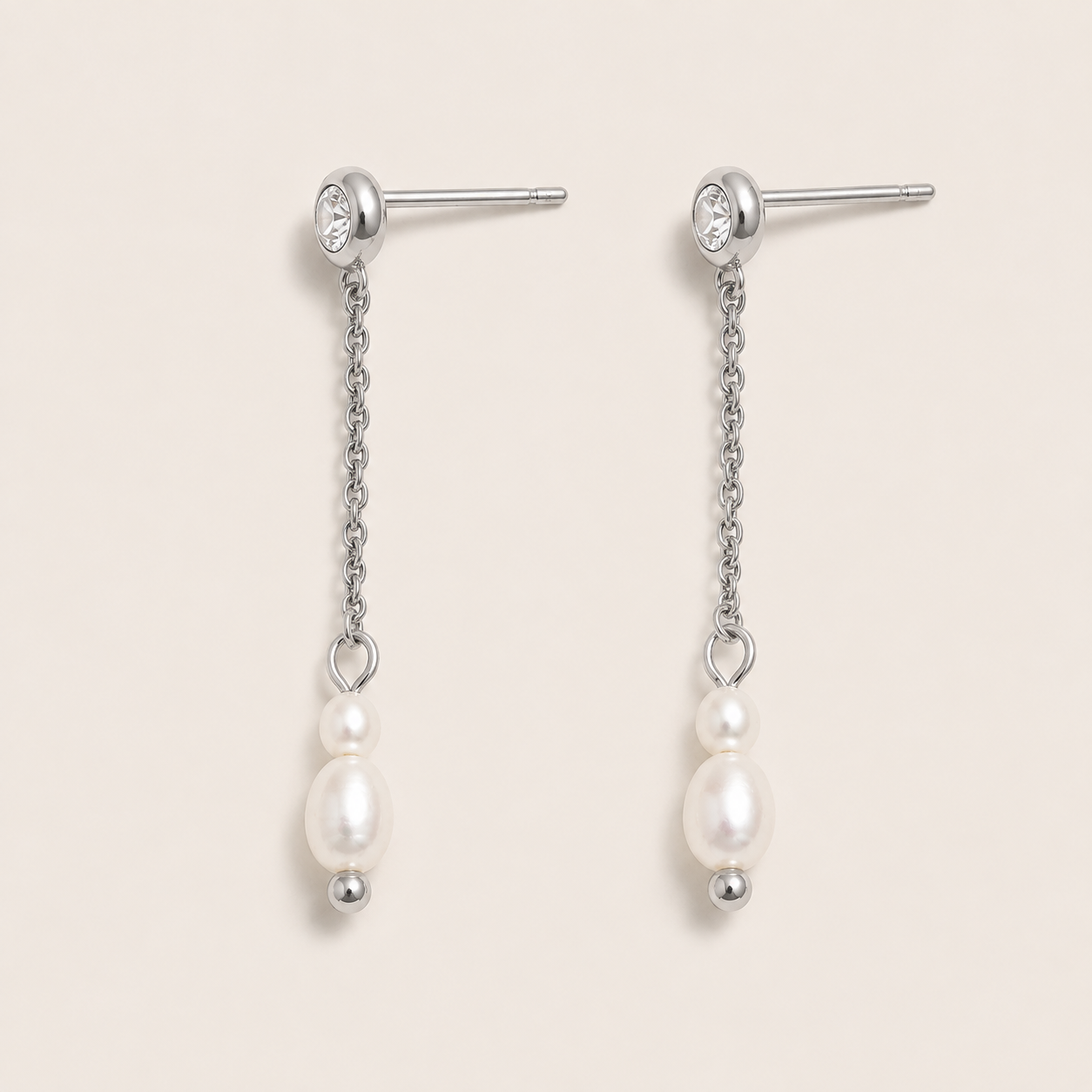 Silver drop earrings with a zirconia stud, fine chain and two pearls on a cream backdrop — Folie à Trois Whisper EARRINGS