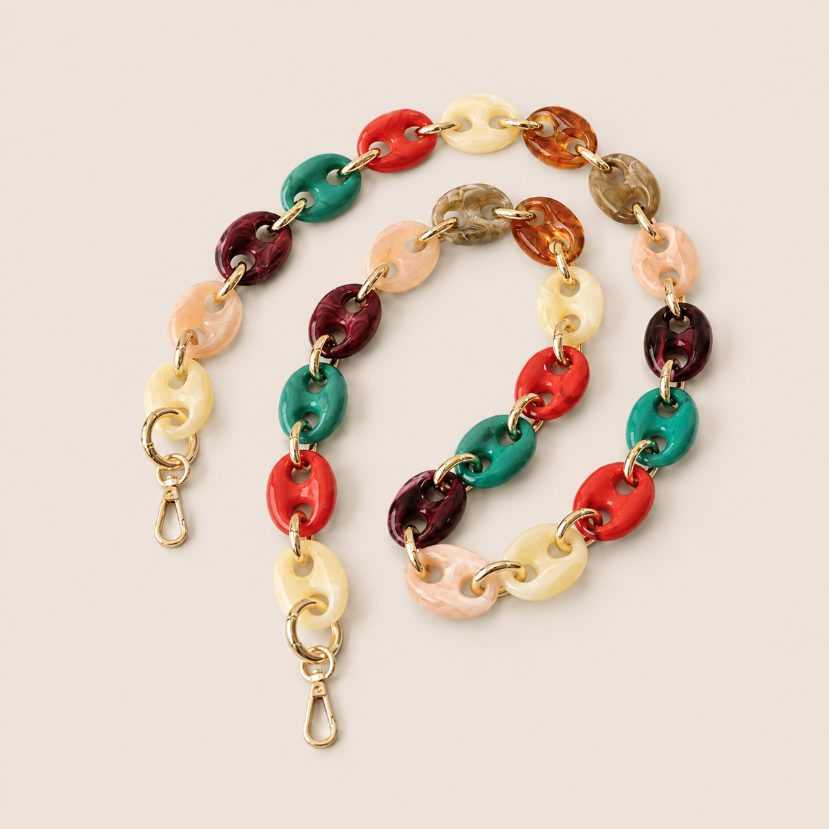 Folie à Trois Wilder long phone chain in multicolor puffed links with gold connectors, coiled on a cream background.