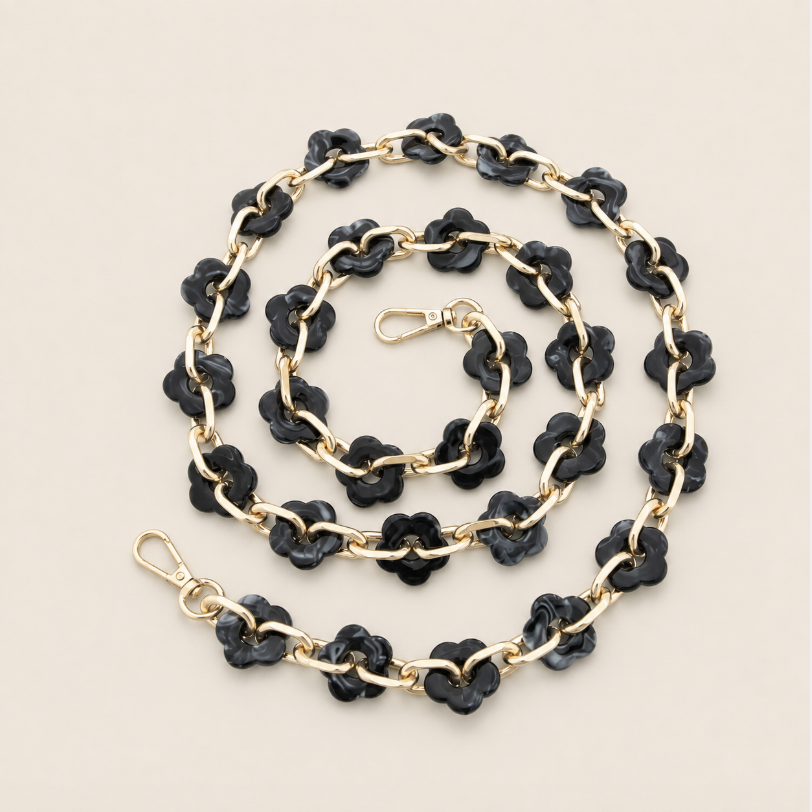 Coiled flower-link phone chain in black acrylic with gold chain links on a cream background — Folie à Trois Zinnia wholesale phone chain