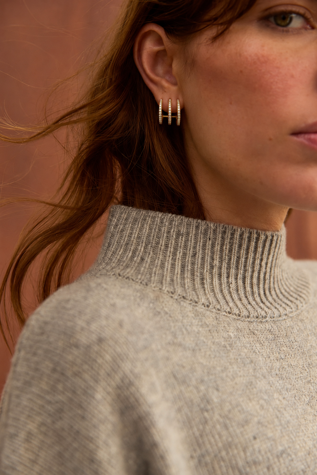 Triad EARRINGS worn in the lobe, three slim gold pavé bands fanned out on one post, beside auburn hair.
