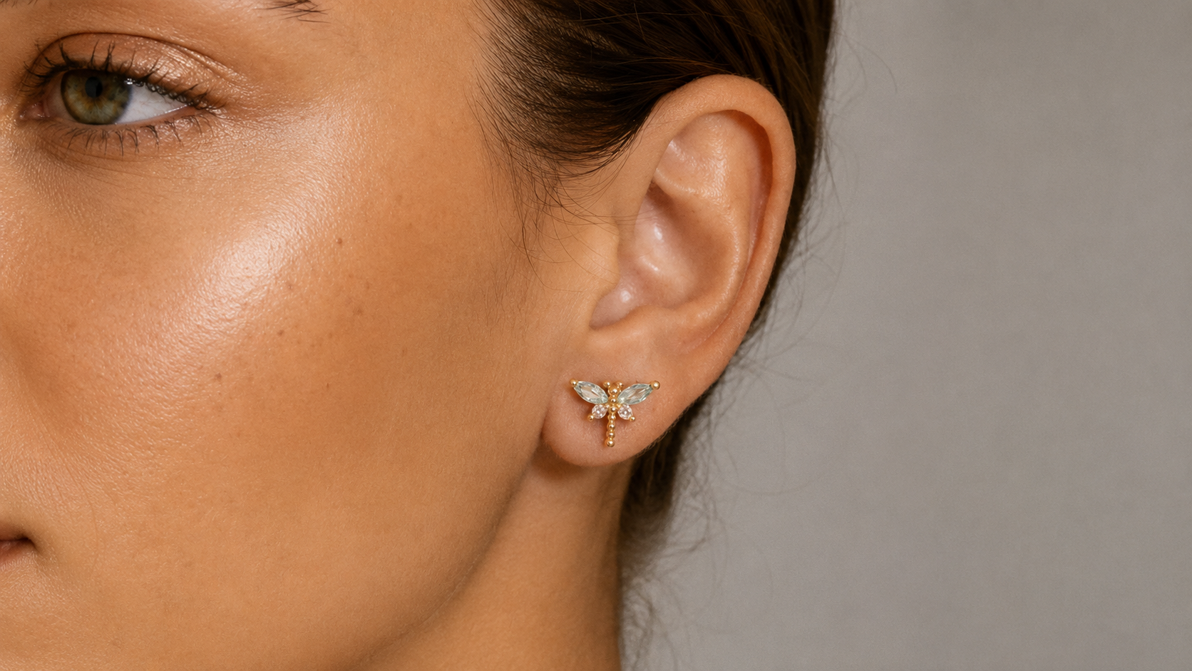 Close-up of a woman's ear wearing a small gold star-shaped stud earring.