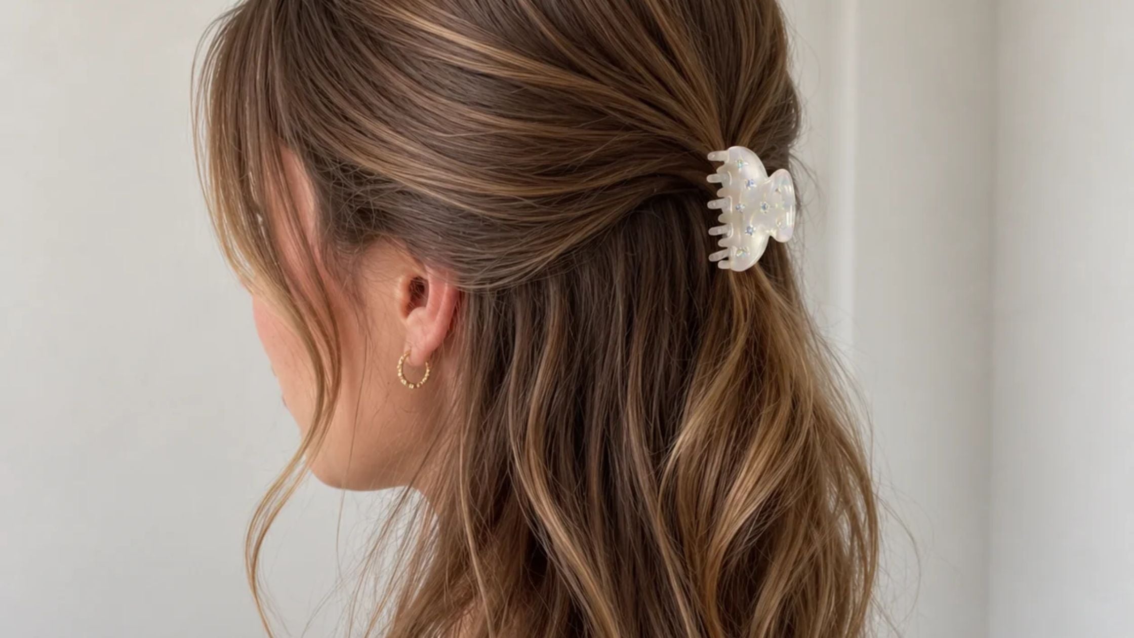 Close-up of wavy brown hair styled with a cream claw hair clip.