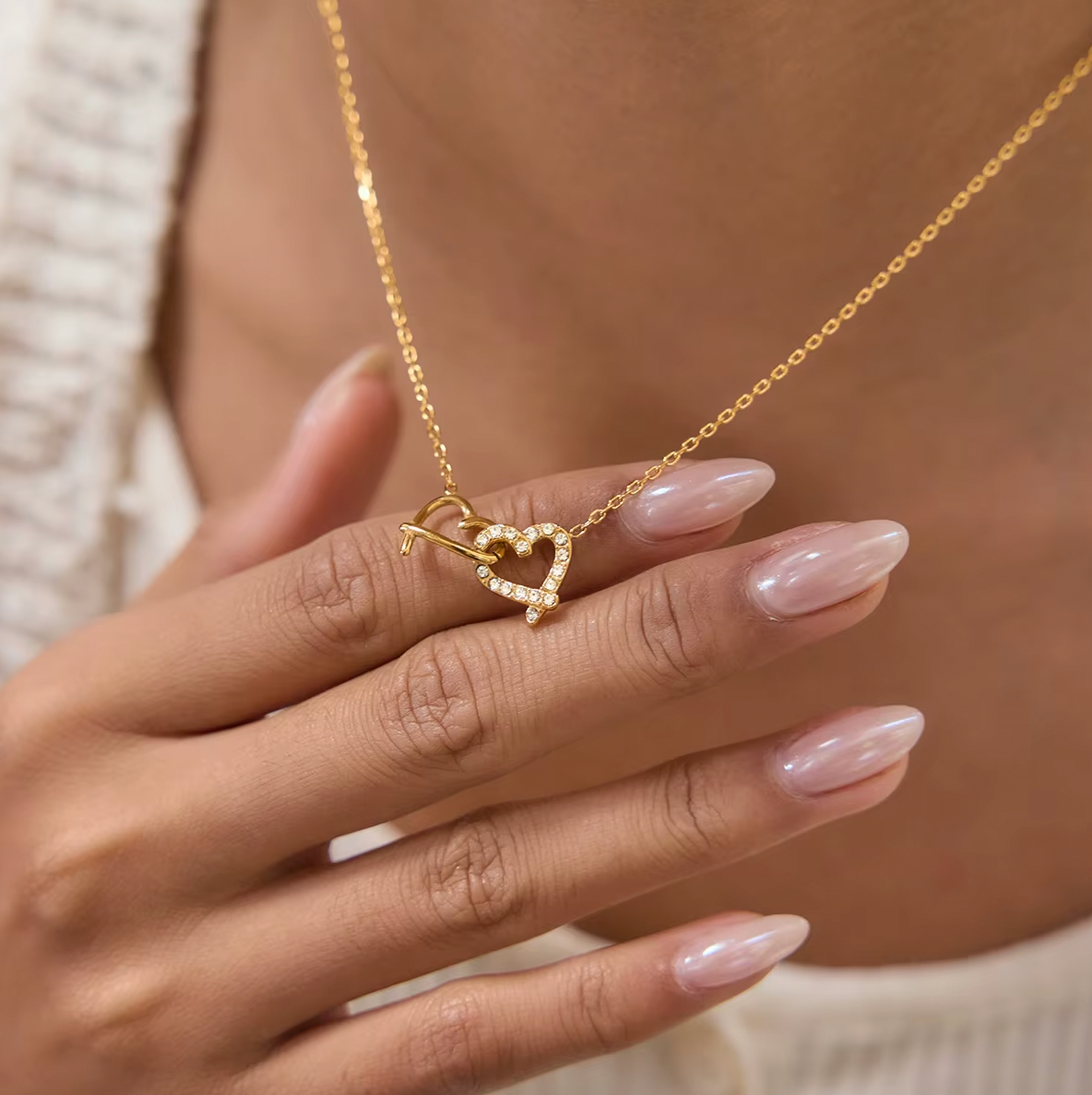 Gold-plated necklace with a delicate chain and interlocking heart-shaped pendant embellished with clear crystals