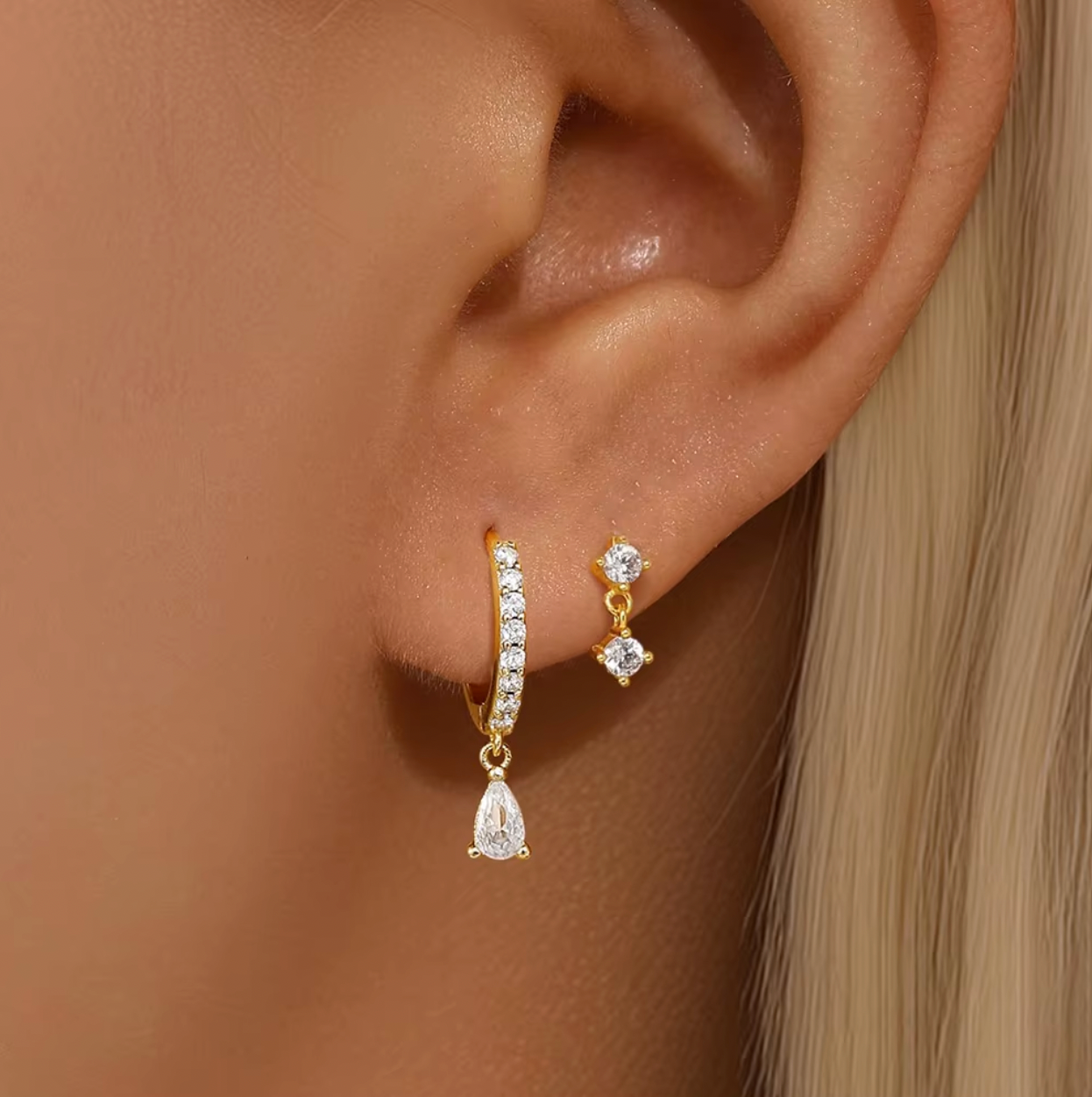 Two matching earring sets displayed on a white background, featuring gold and silver stud and huggie earrings with clear crystal stones and delicate drop charms, arranged vertically.