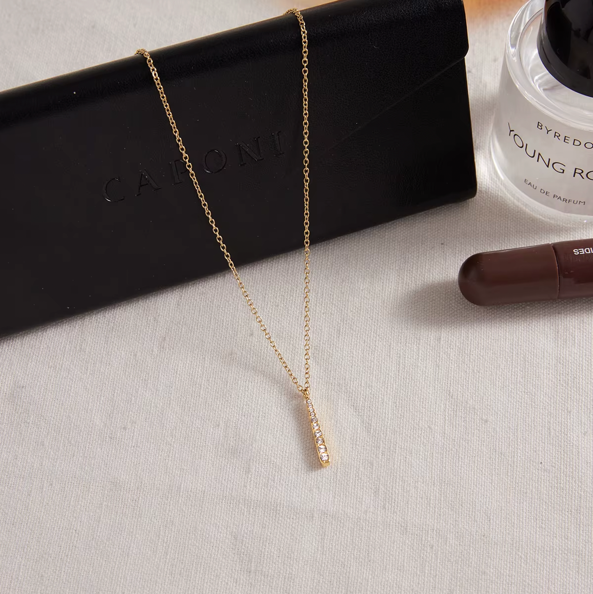Gold-plated necklace with a fine chain and a slim vertical bar pendant set with clear crystal stones