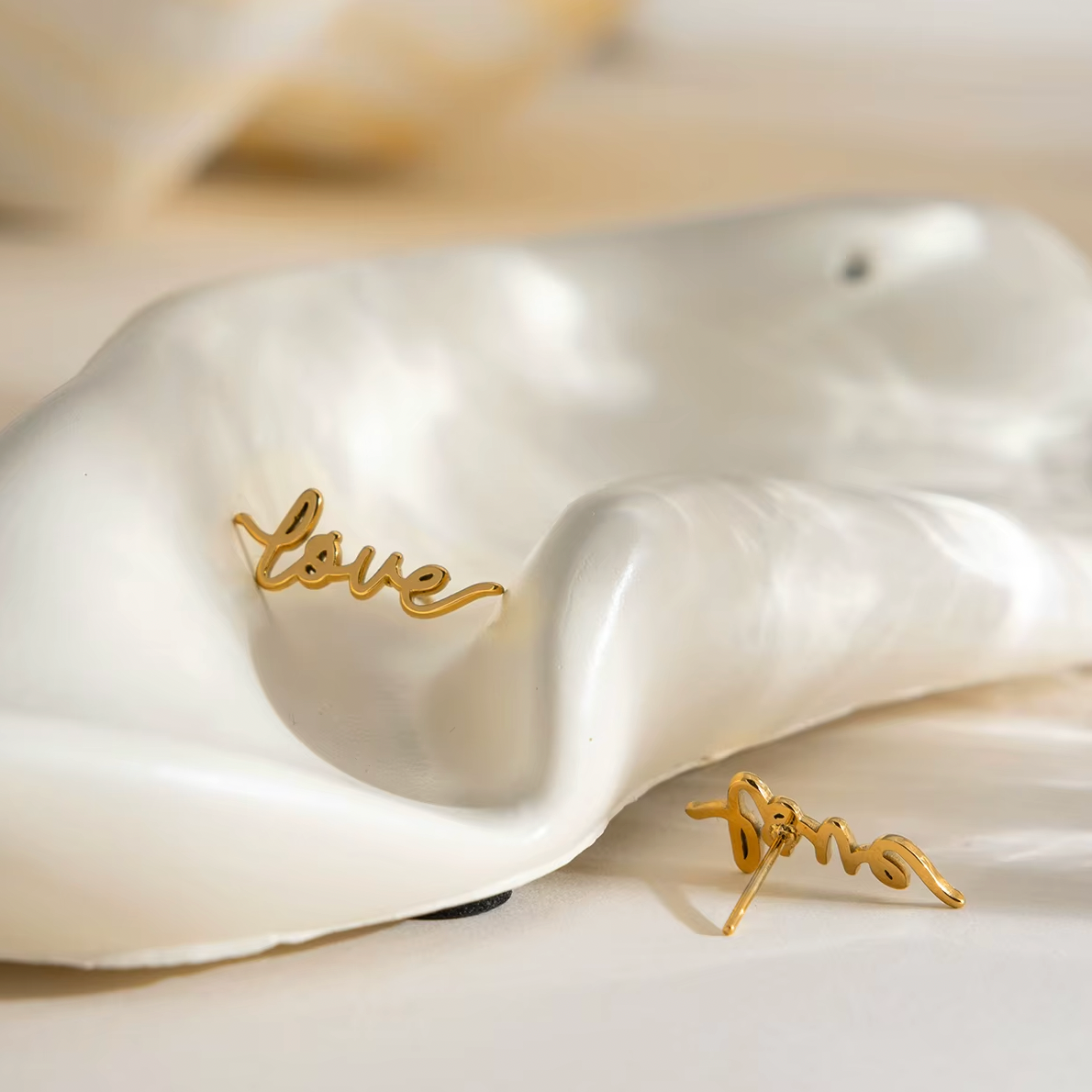 Pair of gold-plated stud earrings spelling “love” in cursive script