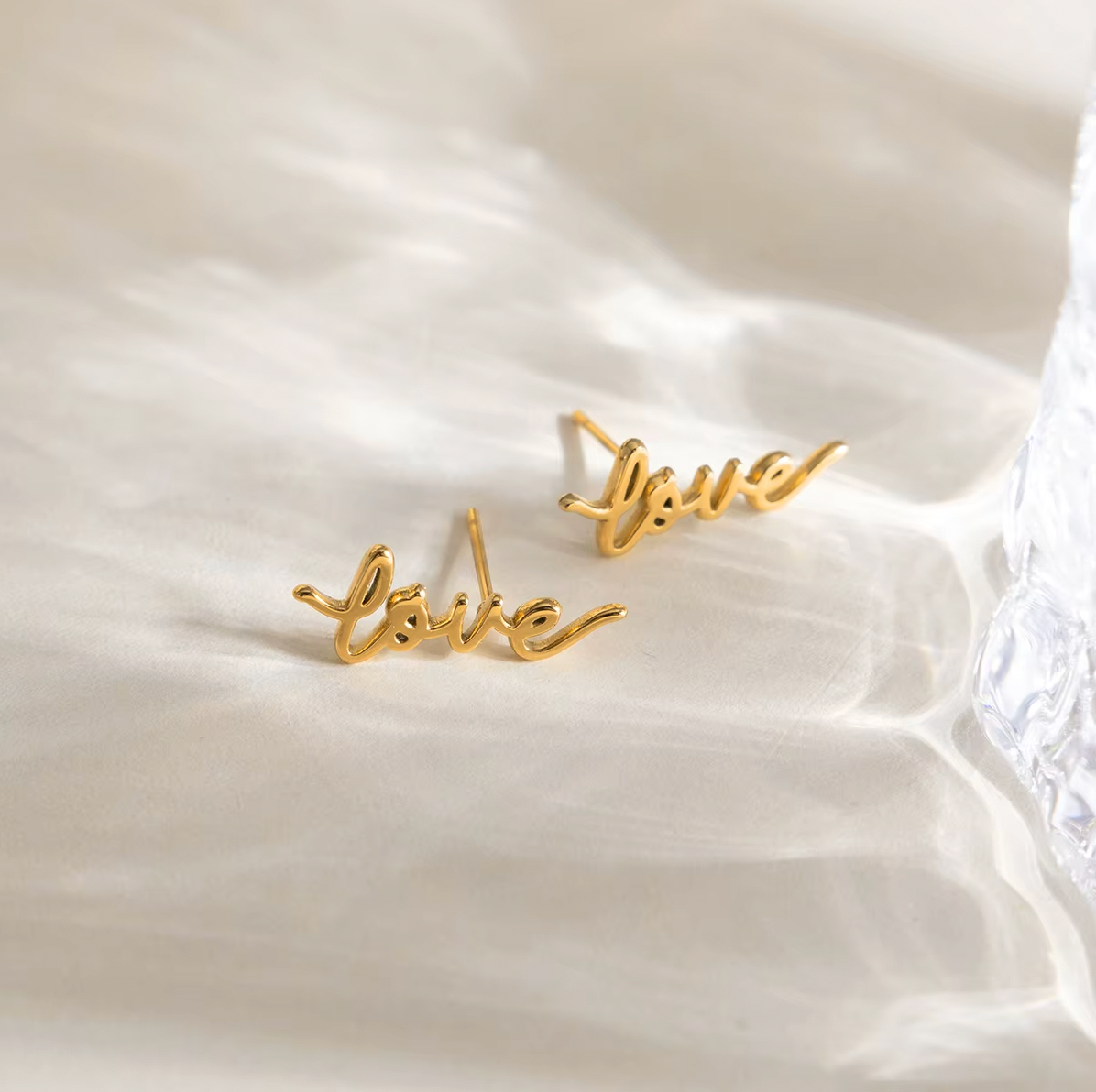 Pair of gold-plated stud earrings spelling “love” in cursive script