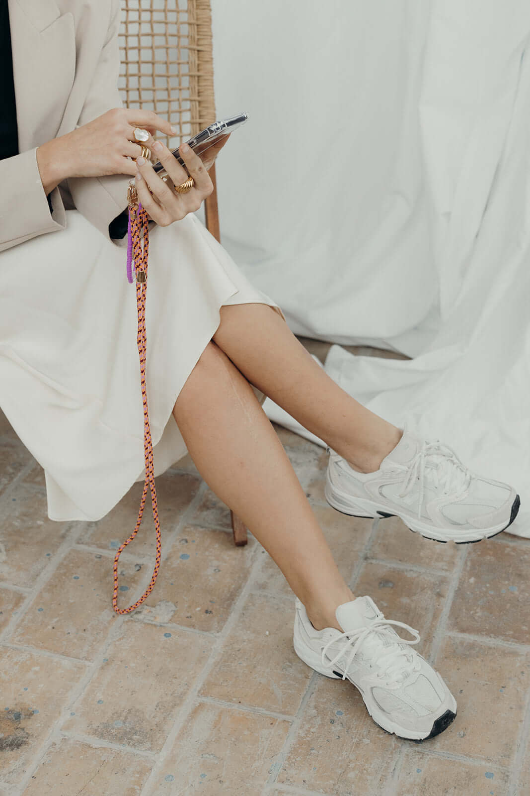 Seated woman holding a phone with a red and white Aesthetic Colorful PHONE CORD dangling at her side.