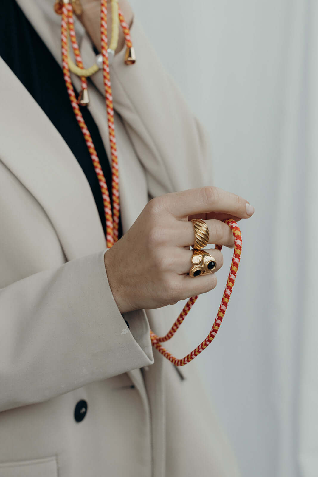 Close-up of a hand with gold rings holding an orange and white Aesthetic Colorful PHONE CORD.