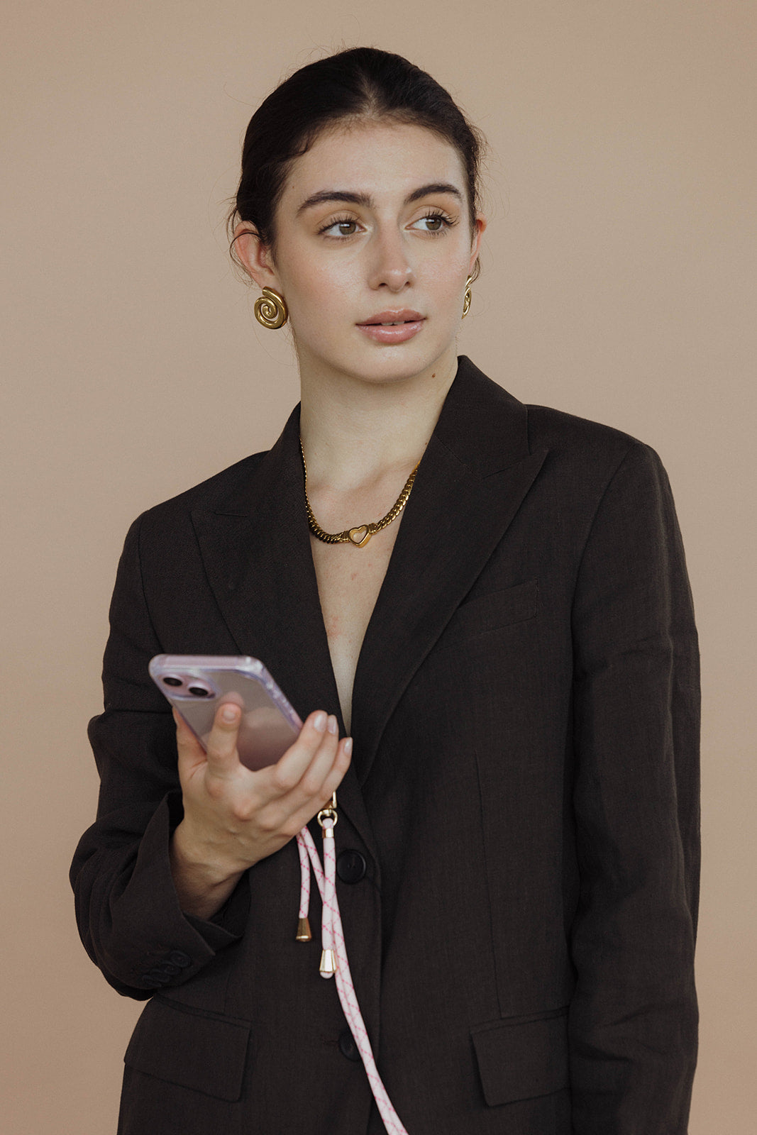 Woman in a dark blazer holding her phone by a pink and white Aesthetic Colorful PHONE CORD.