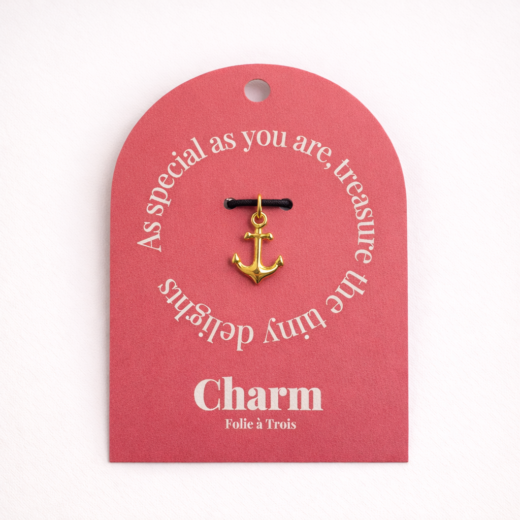 The Anchor CHARM displayed on a coral pink Charm gift tag, hanging from a black cord against the card's text.