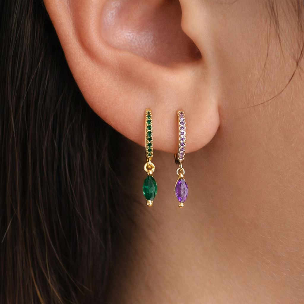 Anette Earrings worn on the ear, mixing an emerald-green and a lilac-purple marquise drop on matching pave hoops.