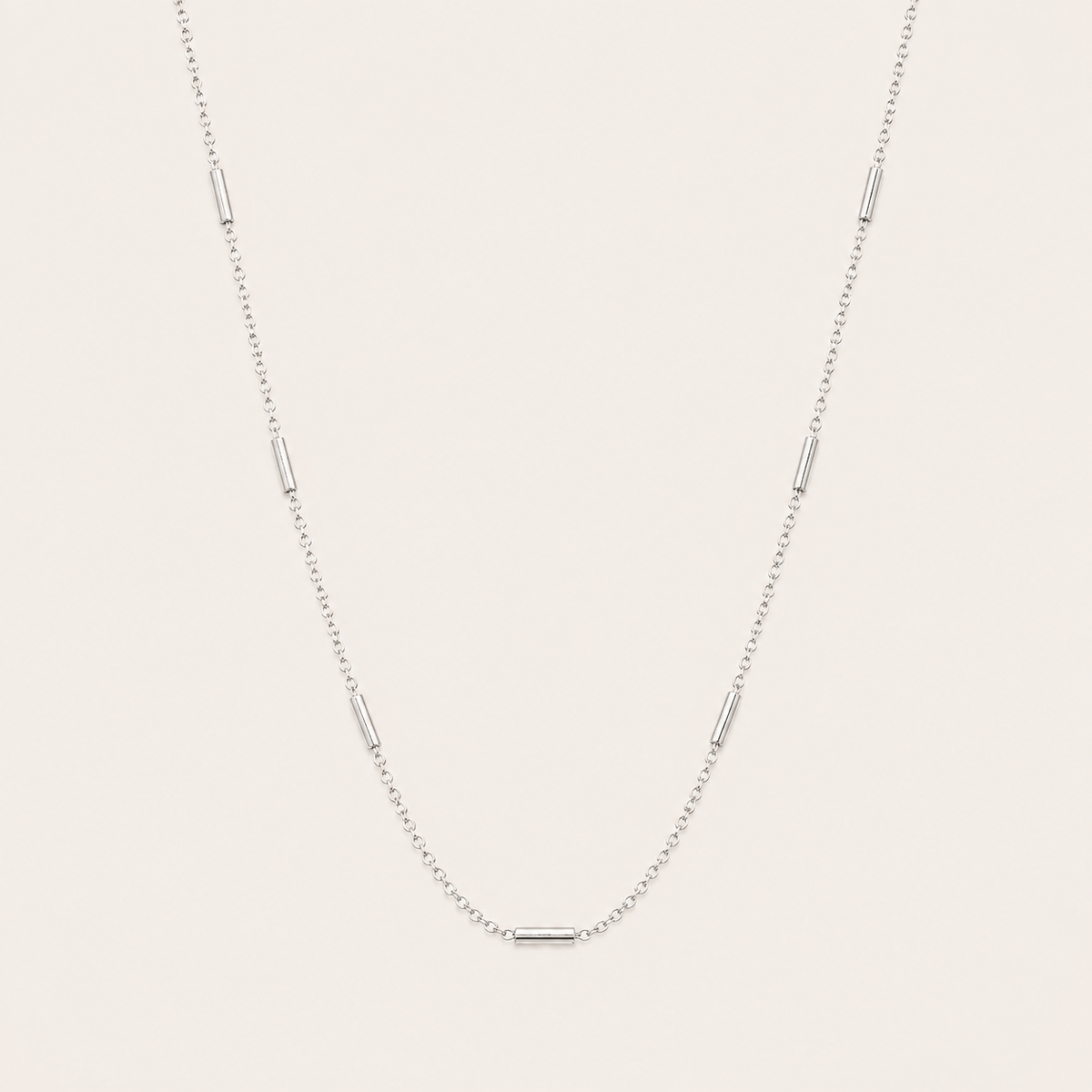 Silver chain necklace with small tube station beads spaced along the length, the Asta NECKLACE, shown in a close-up studio shot.