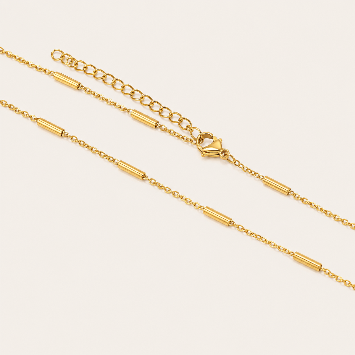 Gold and silver Asta NECKLACE chains shown together in close-up, highlighting the tube station beads and adjustable clasp.